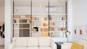 A modern living room with a white sofa, a side table, and a bookshelf filled with books.