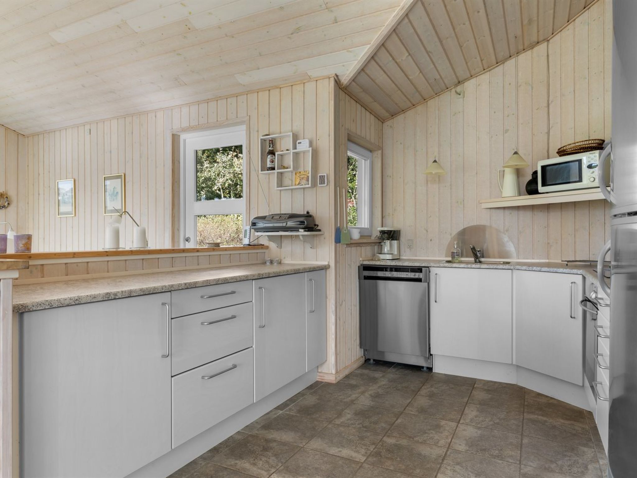 A modern kitchen with white cabinets, a dishwasher, a microwave, and a sink.