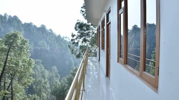 A building with a balcony overlooking a forested valley. - Asha Residency By St Hotel (Shimla)