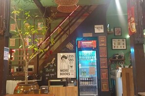 A bookstore with a variety of bookshelves, a coffee machine, and a refrigerator.