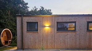A wooden cabin with two windows, a small attached structure, and a wooden archway.