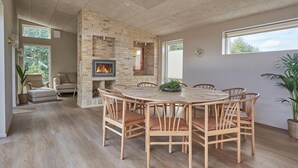 A spacious dining area with a brick fireplace, wooden dining table, and chairs.