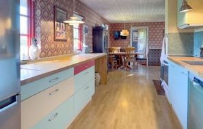 A kitchen with wooden cabinets, a dining table, and a TV.