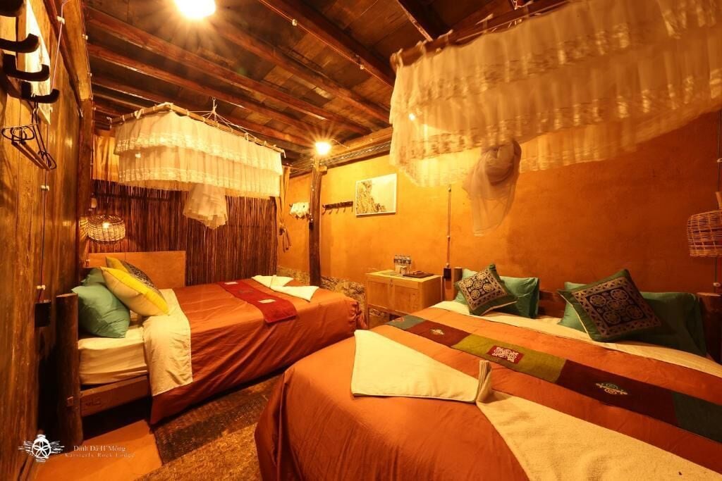 A cozy room with two beds, wooden beams, and hanging curtains.
