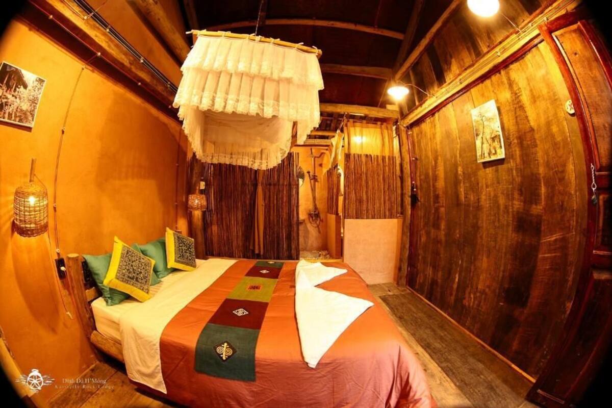 A traditional room with a bed, wooden walls, and a hanging white canopy.