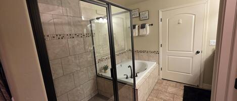A bathroom with a glass-enclosed shower, a bathtub, and a door.