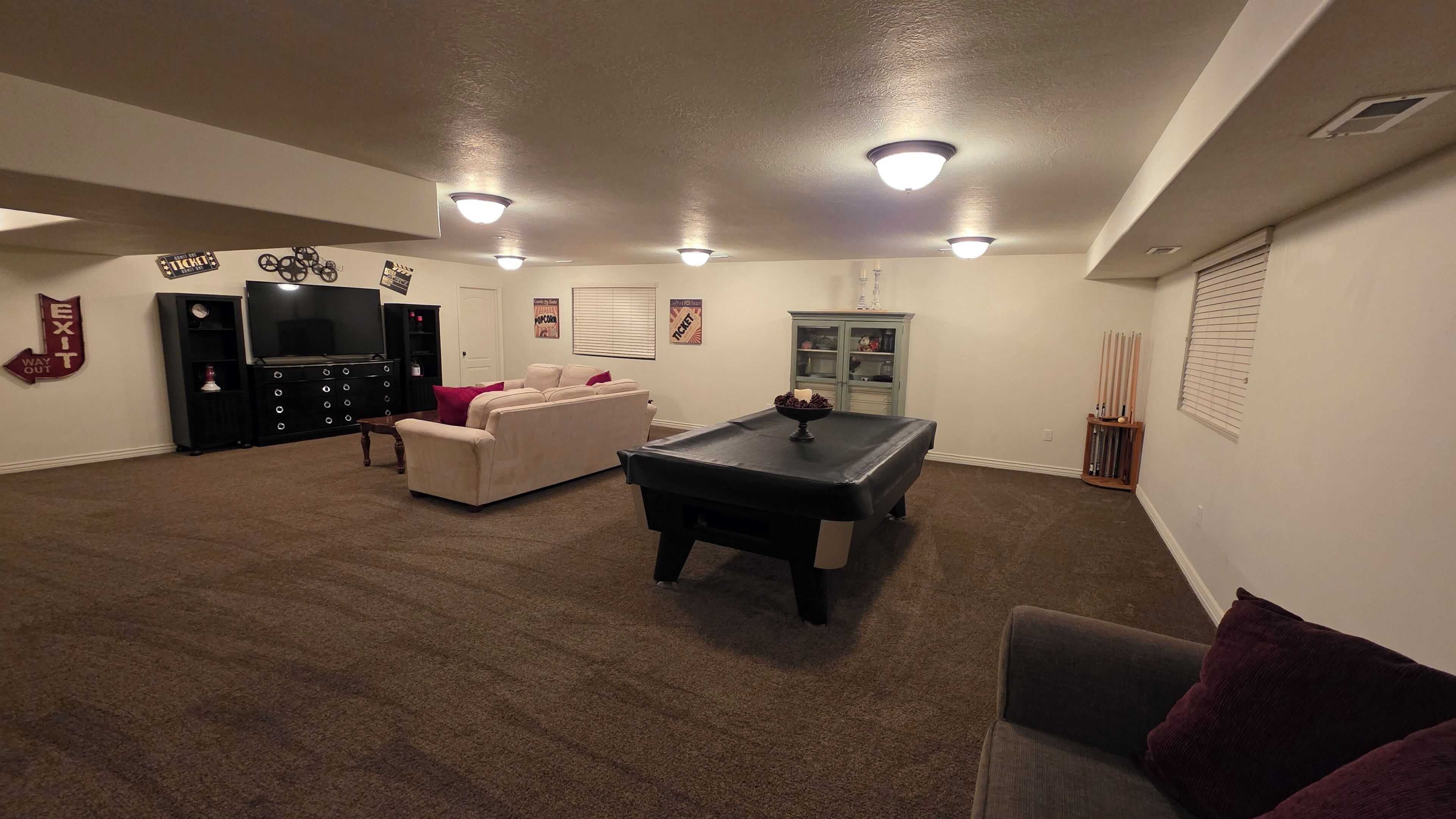 Een ruime woonkamer met een pooltafel, een bank en een televisie.