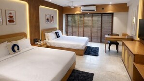 Una habitación de hotel con dos camas, un escritorio, una silla, un televisor y un ventilador de techo.