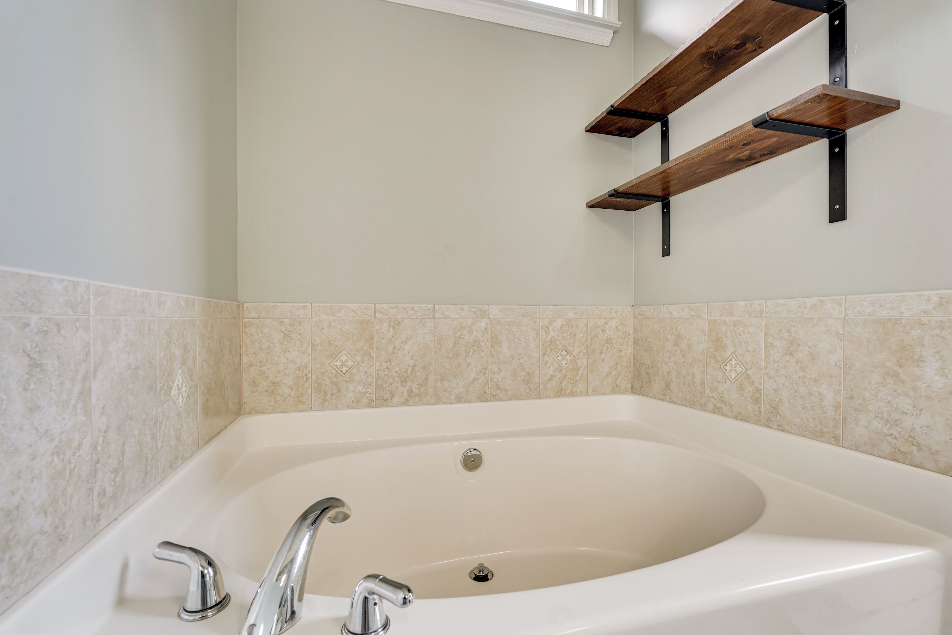 Une salle de bain avec une baignoire sur pieds, une étagère fixée au mur et un sol carrelé.