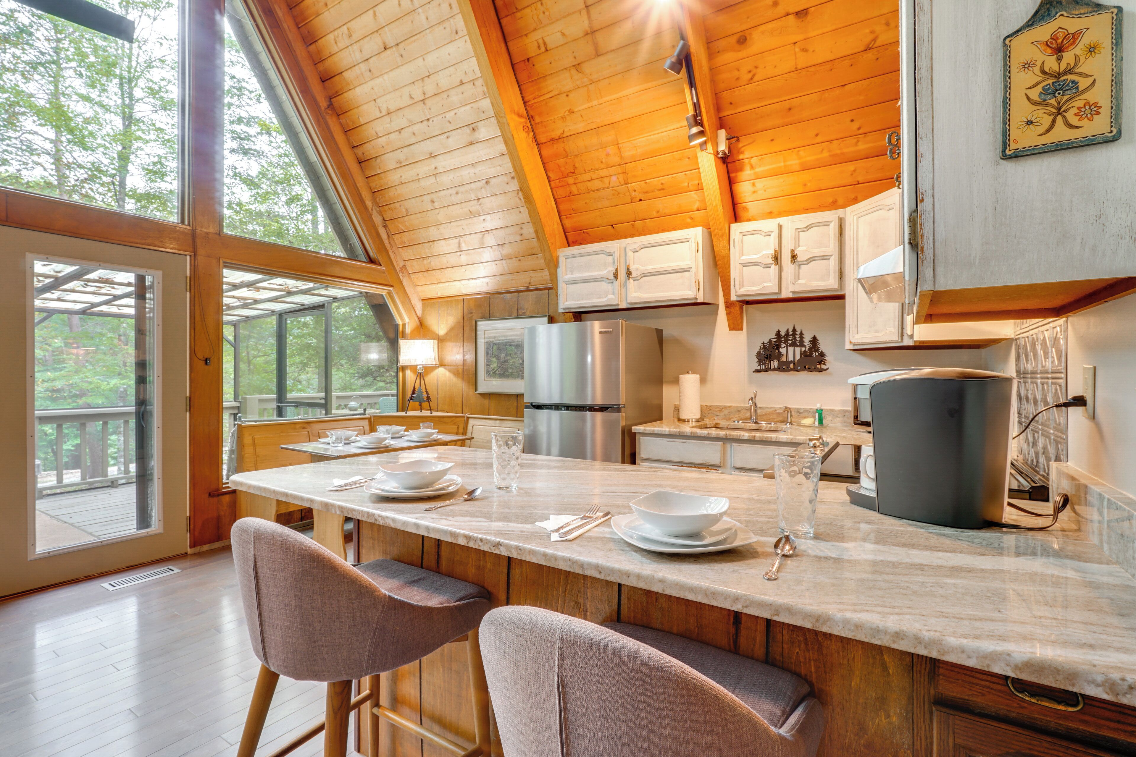 Una cocina moderna con vigas de madera, una isla grande con asientos tipo barra y vistas al exterior.