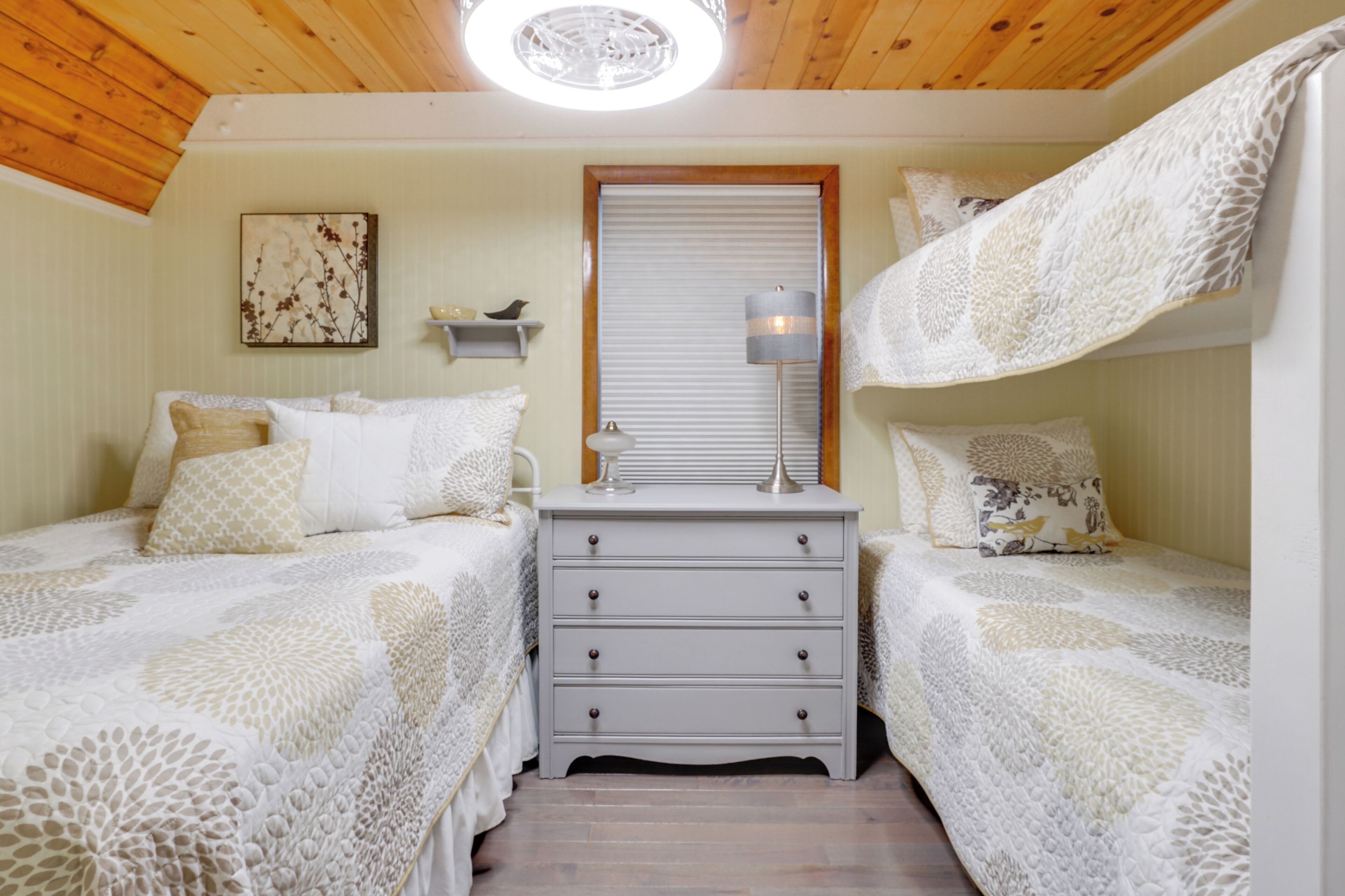 A bedroom with two beds, a nightstand, a lamp, and a framed picture on the wall.