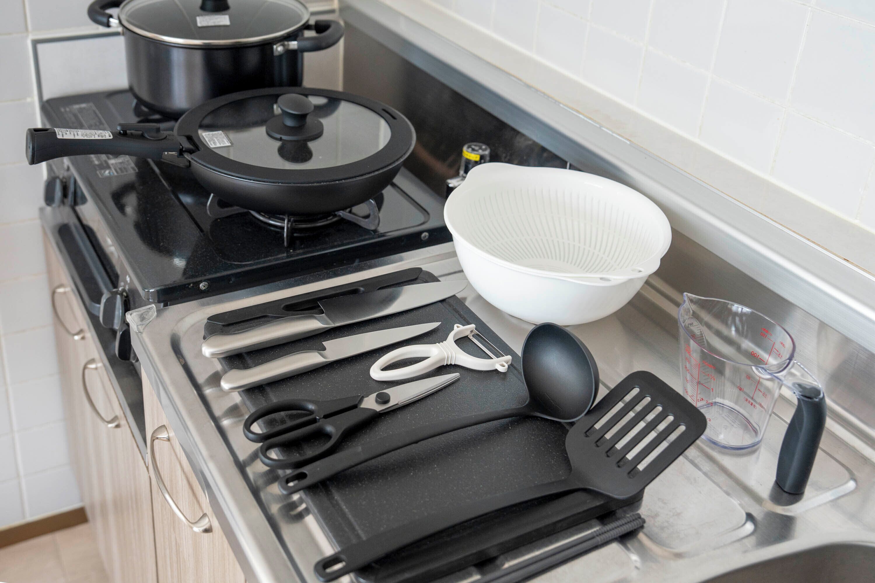 A kitchen with a stove, pots, and various utensils like scissors, a ladle, and a measuring cup.