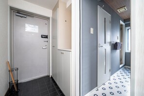 A hallway with a door, a towel rack, and a broom leaning against the wall. - MOTTO (Sapporo)