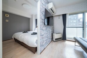 A modern bedroom with a bed, a bench, a TV, and a large window. - MOTTO (Sapporo)