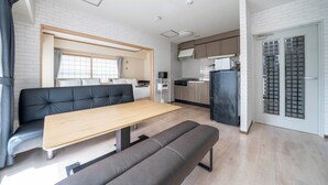A modern, compact living space with a dining area, sofa, and kitchenette. - MOTTO (Sapporo)