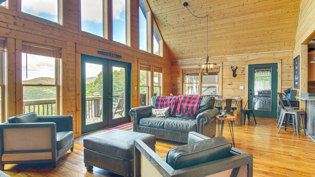 A spacious room with leather furniture, large windows, and a wooden interior. - Ski & Hike: Mars Hill Mountaintop Cabin w/ Views (Mars Hill)