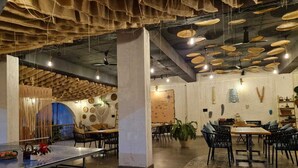 A spacious restaurant with high ceilings, hanging baskets, and a variety of seating arrangements. - Casa Rossa Resort (Pune)
