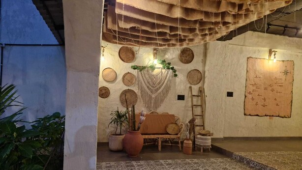 Ein Zimmer mit rustikalem Dekor, mit gewebten Körben an der Wand, einer Holzleiter und einer Karte.