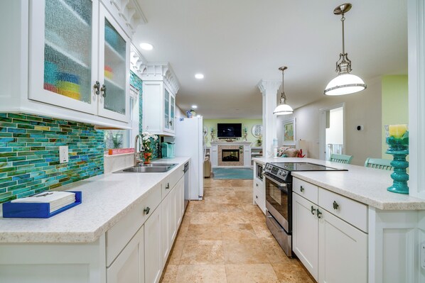 A modern kitchen with white cabinets, a tiled backsplash, and a central island. - Outdoor Oasis w/ Bar & Lanai: Tavares Escape (Tavares)