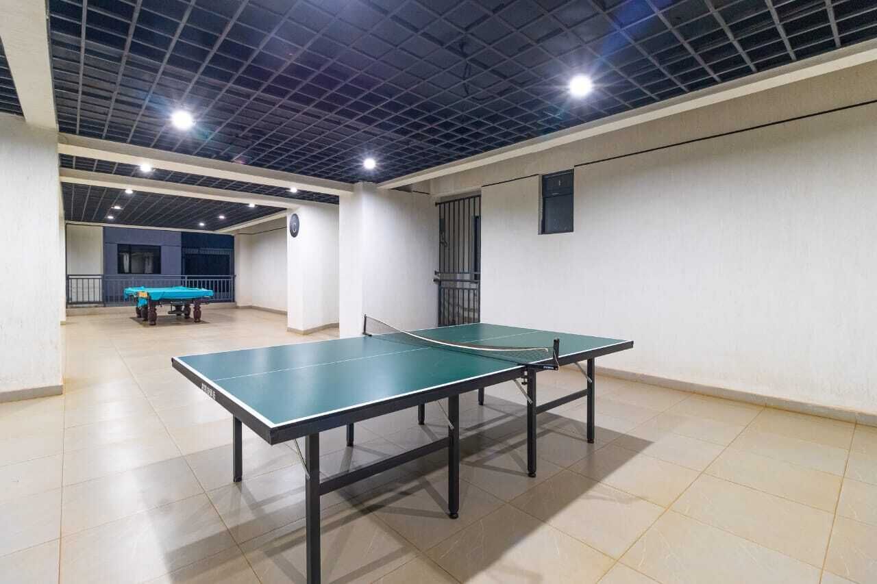 A ping pong table in a well-lit indoor space with a tiled floor and a high ceiling.