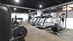 Un gimnasio con cintas de correr, máquinas de pesas y una máquina de remo.
