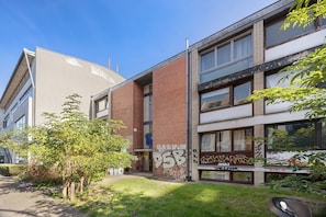 Un bâtiment à la façade en briques, doté de grandes fenêtres et dont les murs sont couverts de graffitis.