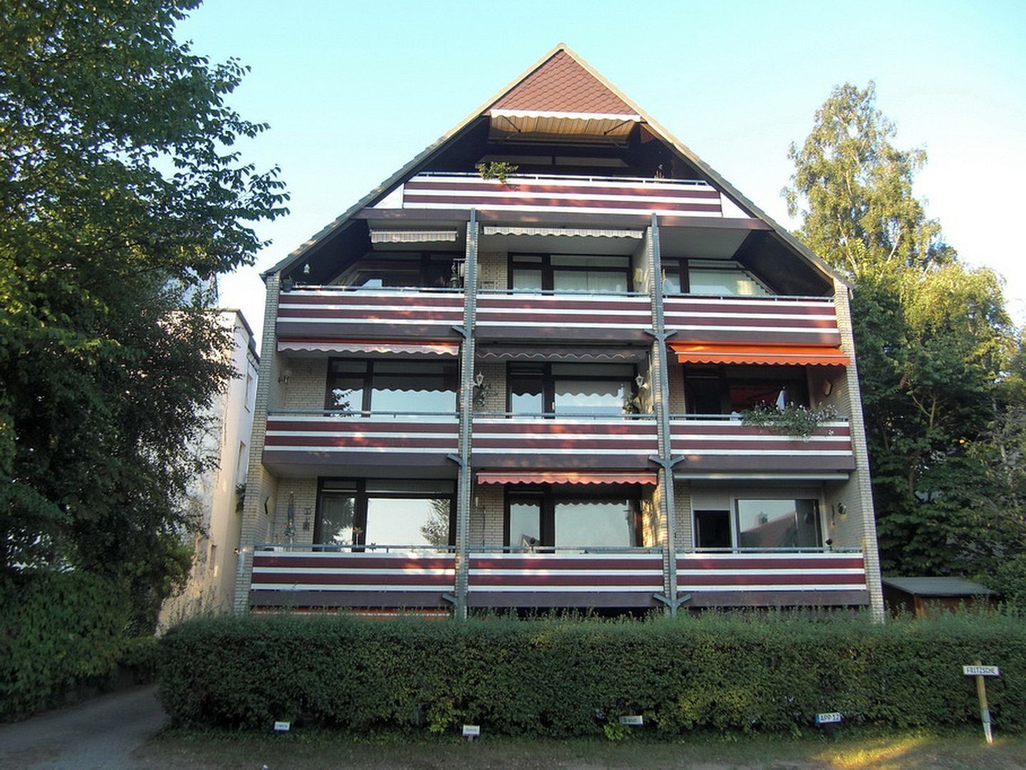 A multi-story building with a flat roof, multiple balconies, and a brick facade.