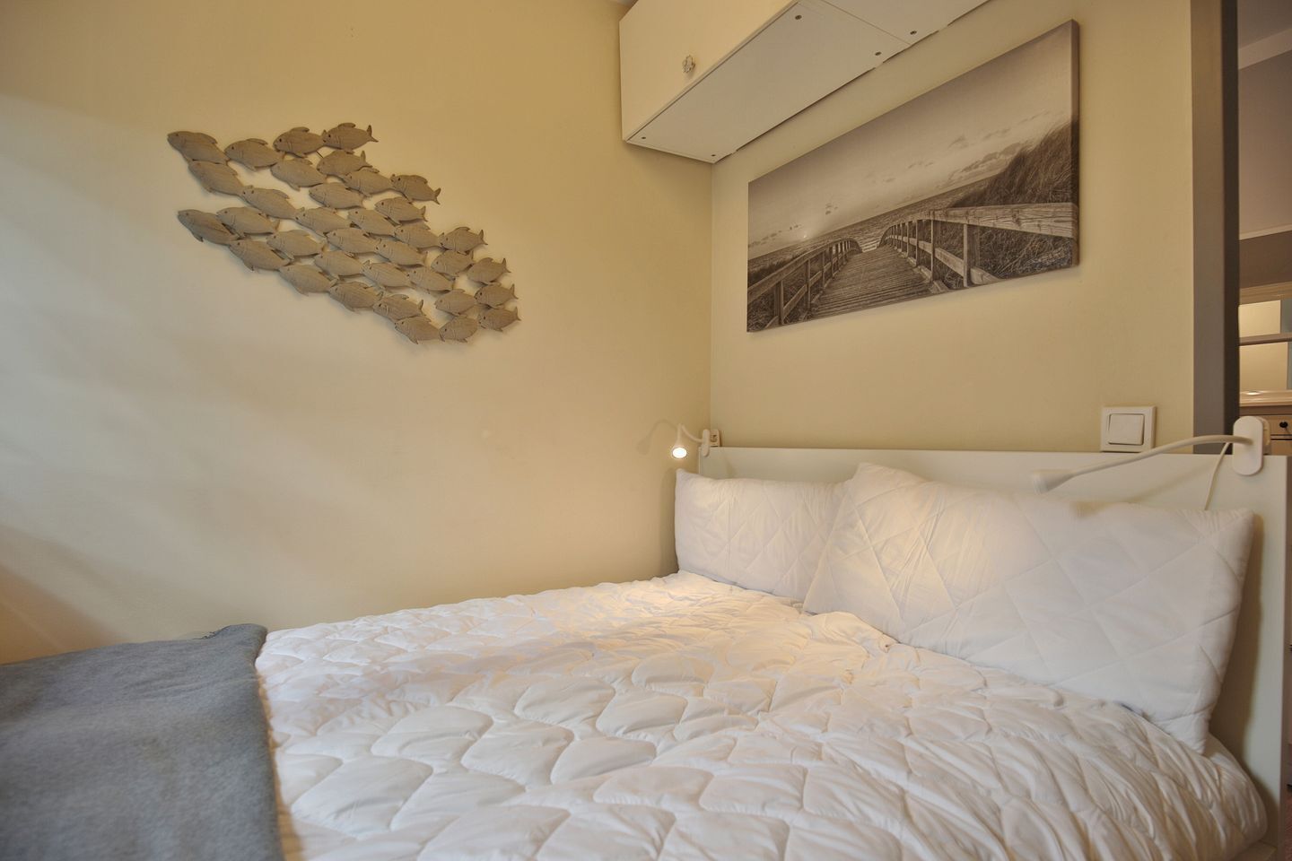 A bedroom with a bed, a wall-mounted artwork, and a ceiling light.