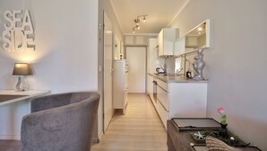 Eine moderne Küche mit weißen Schränken, einer Arbeitsplatte und einem Spülbecken. Im Vordergrund stehen ein Stuhl und ein Tisch mit einer Lampe.