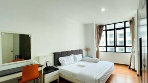 A hotel room with a bed, a desk, a chair, a mirror, and a window with curtains. - Lake view Resisdence (Seri Kembangan)