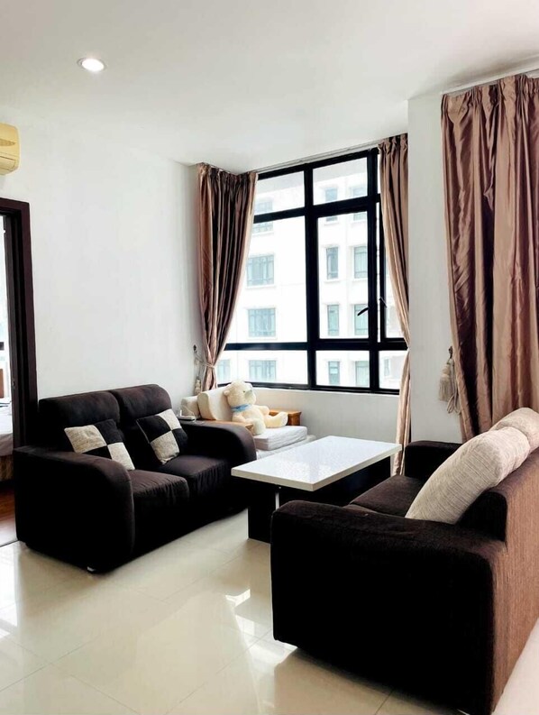 A modern living room with a sofa set, a coffee table, and a large window with curtains.