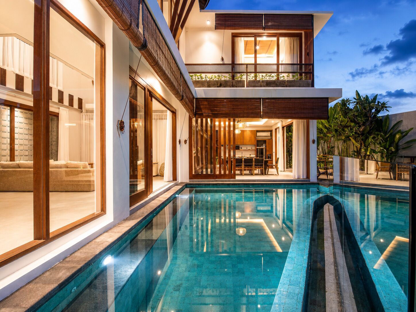 A modern two-story house with a swimming pool, large windows, and a dining area.