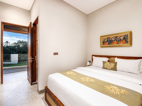 A bedroom with a bed, a door leading to a balcony, and a wall-mounted painting.