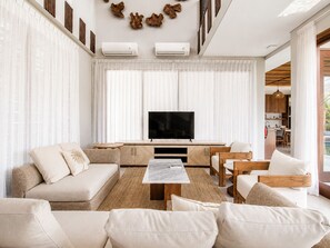 A modern living room with a TV, sofa, and dining area.