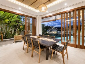 A dining area with a large table, chairs, and a view of a swimming pool.