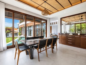 A modern kitchen with a large island, wooden cabinets, and a view of a swimming pool.