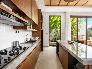 A modern kitchen with wooden cabinets, a black refrigerator, and a large window.