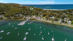 Vue aérienne d’une zone côtière avec un port de plaisance, des bateaux et des maisons.