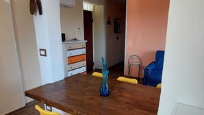 Een eethoek met een houten tafel, gele stoelen en een blauwe vaas.