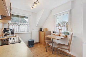 A compact kitchen with a microwave, toaster, and sink. There's a small trash bin and a window with a star decoration.