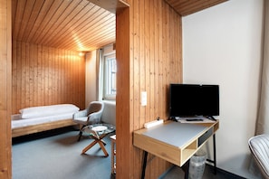 A compact room with a bed, a desk with a TV, a chair, and a small table. - Apartment 'Zimmer 31' (Nürtingen)