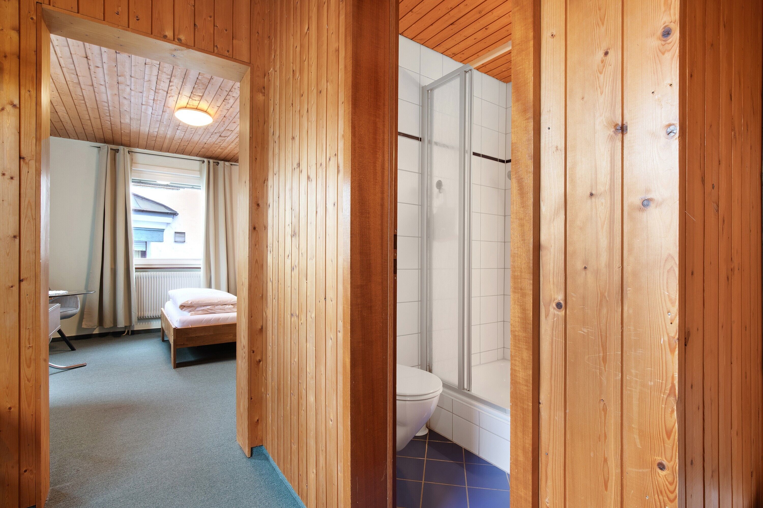 Un interior de madera con una cama, un inodoro y una zona de ducha.