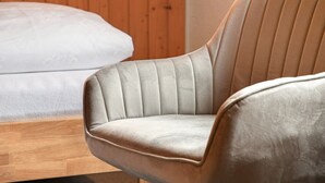 A modern room with a wooden floor, a beige upholstered chair, and a white mattress. - Apartment 'Zimmer 31' (Nürtingen)
