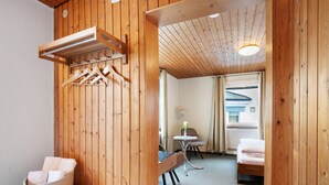 A wooden interior with a bed, a chair, a table, and a hanging rack. - Apartment 'Zimmer 31' (Nürtingen)