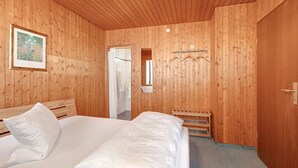 A wooden-paneled room with a bed, a bench, a framed picture, and a mirror. - Apartment 'Zimmer 32' (Nürtingen)