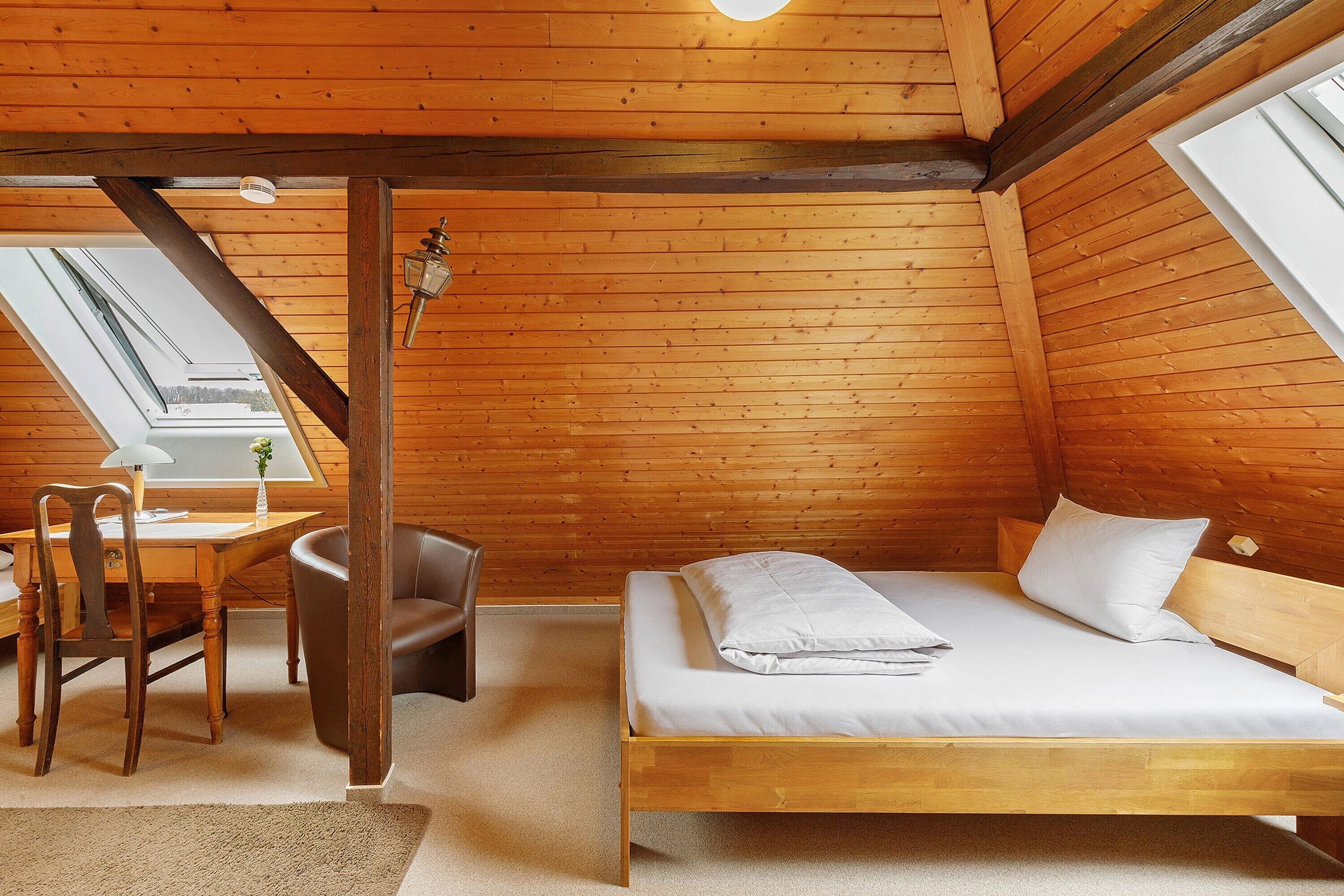 Una habitación de madera con una cama, un escritorio y una silla.