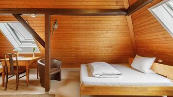 Una habitación de madera con una cama, un escritorio y una silla.