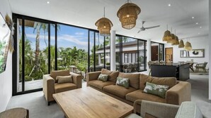A spacious living area with large windows, a sofa set, a wooden coffee table, and hanging pendant lights. - Villa Maxime by BaliSuperHost (Bali)
