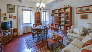 Una sala de estar acogedora con comedor, muebles de madera, una estantería y un televisor.