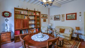 Una sala de estar acogedora con una mesa de comedor de madera, un sofá y una estantería llena de libros.
